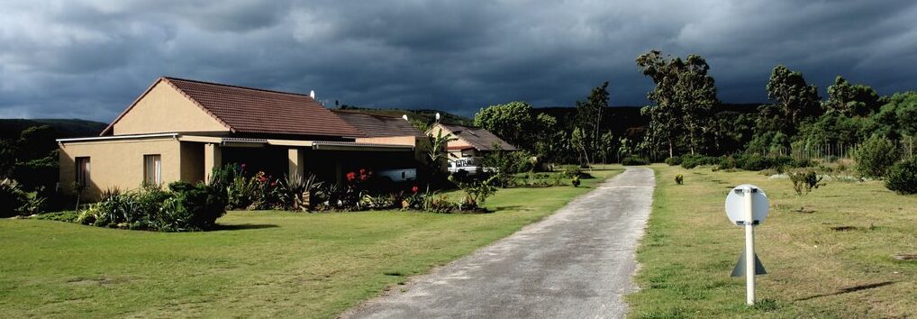 The cottage and its driveway under a dramatic sky