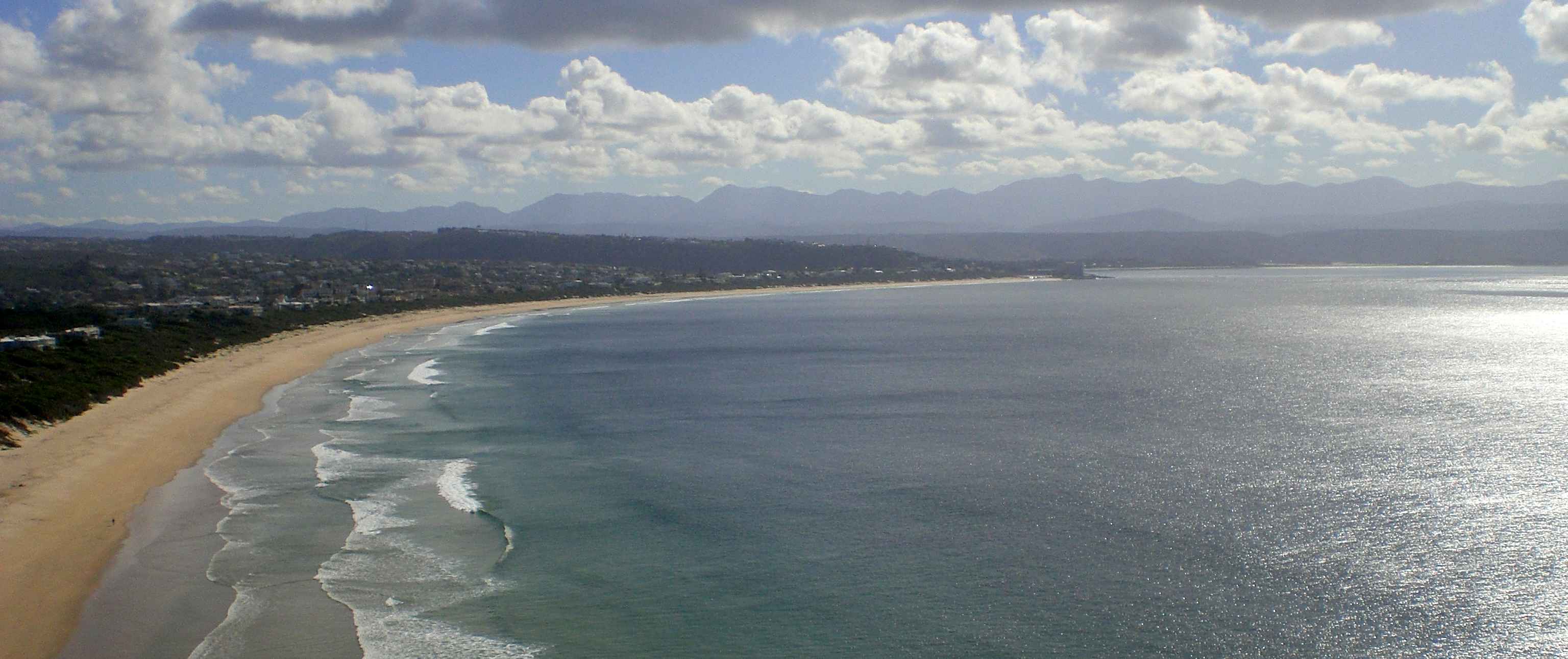 Robberg Beach curving along the bay with mountains in the distance